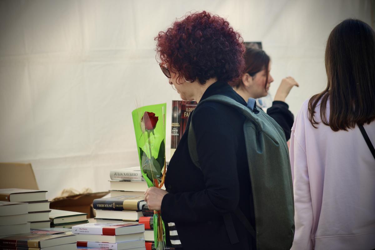 Una dona amb una rosa en una parada de llibres de Sant Jordi a Barcelona