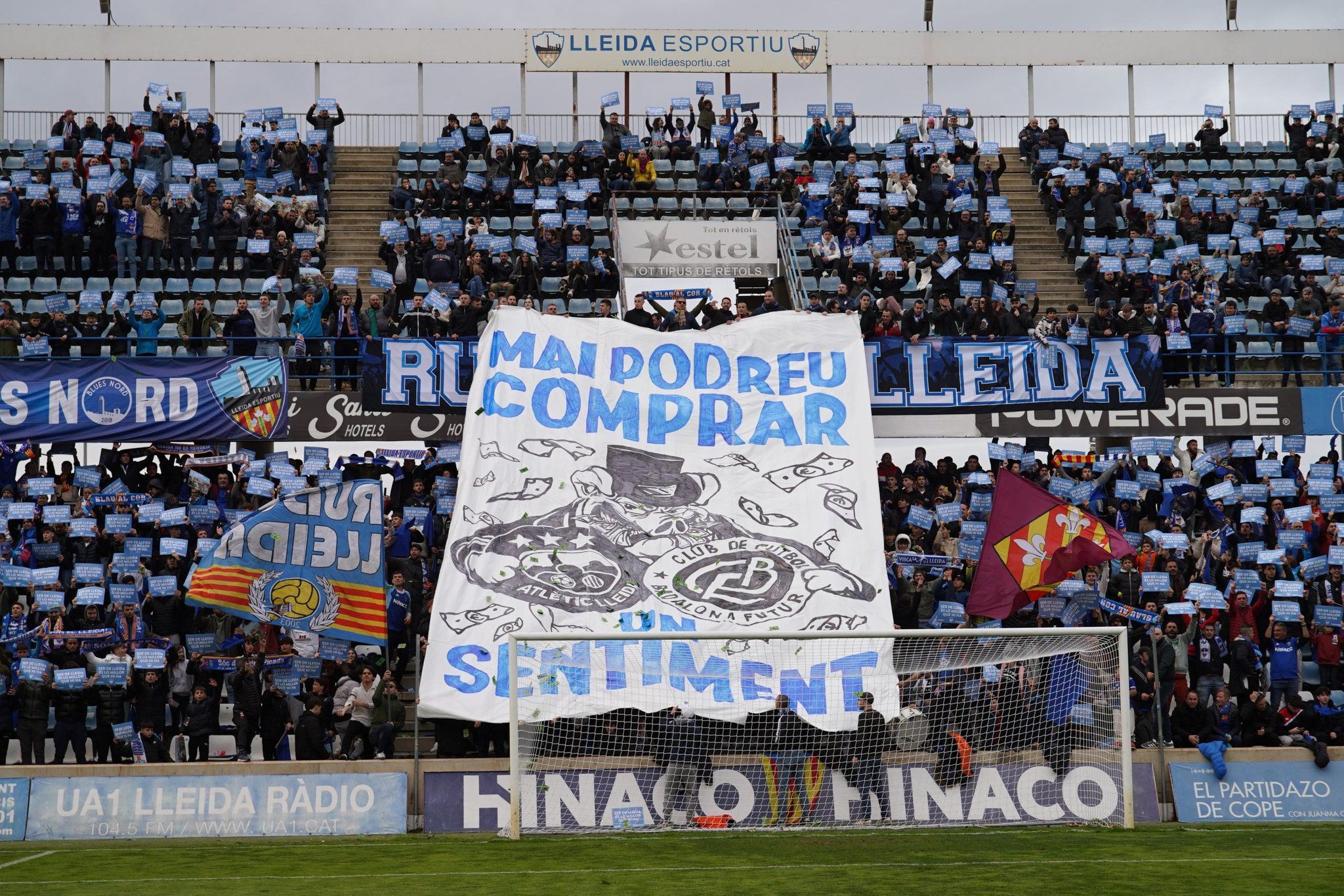 El Gol Nord del Camp d'Esports despenja una pancarta amb el lema: "Mai podreu comprar un sentiment", amb els escuts de l'Atlètic Lleida i el Badalona