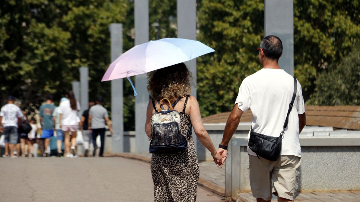 Una dona camina amb un paraigua per protegir se de la calor a Lleida