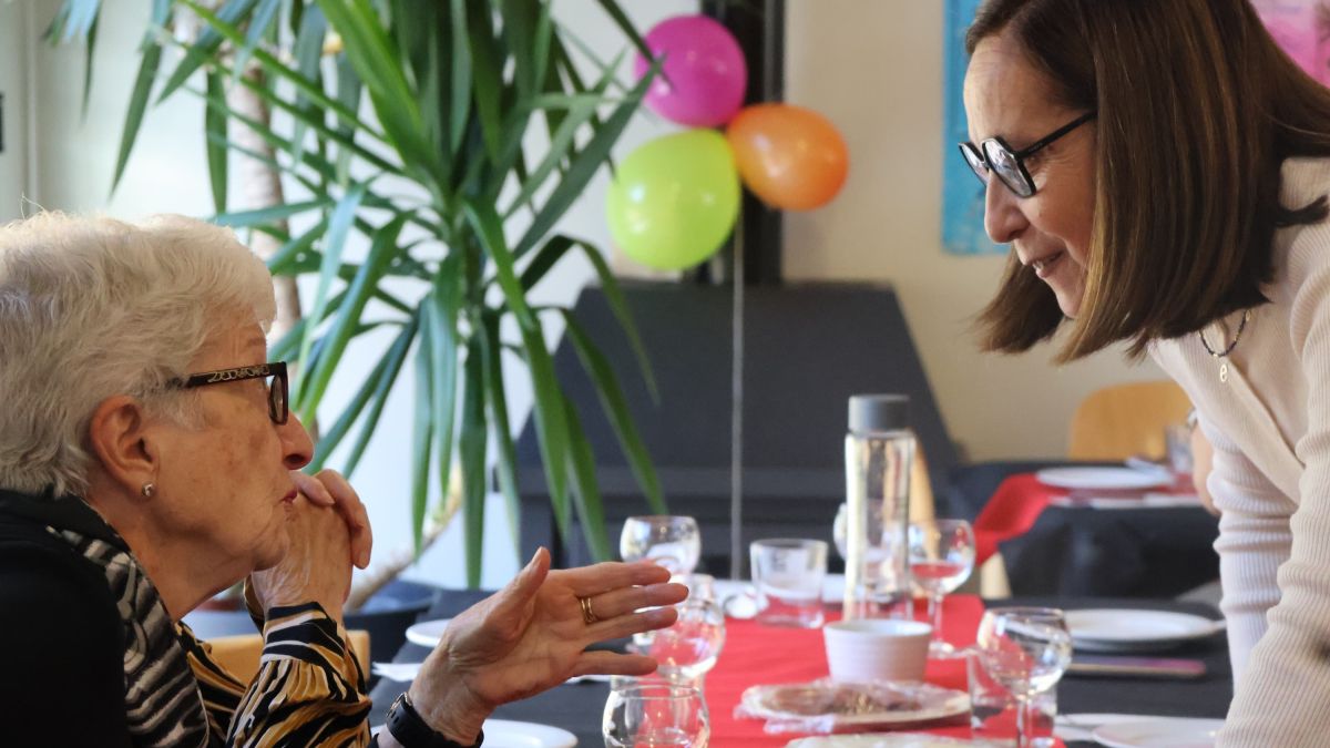 La consellera de Social, Eva Ramos, amb les persones assistents al dinar de celebració dels 10 anys de la llar de Lòria a l'edifici Glòria 1