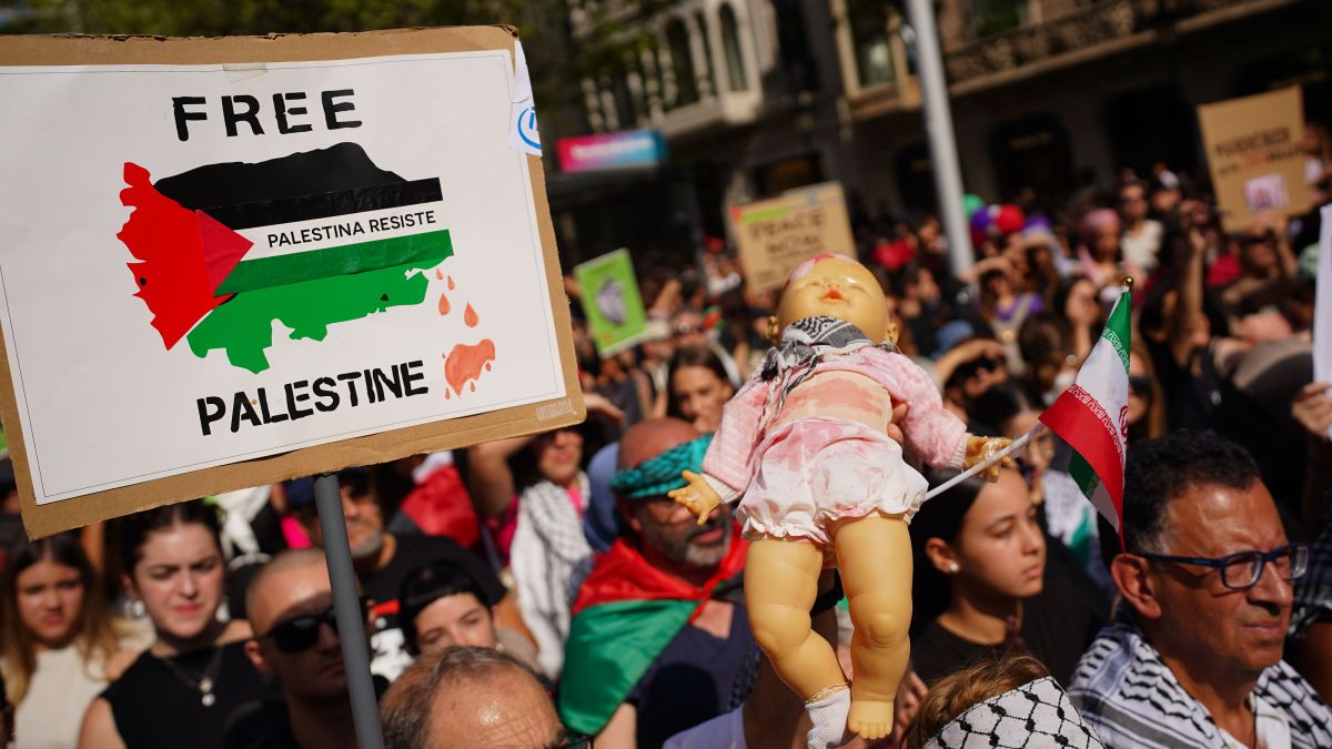 Una pancarta i un nino de plàstic amb el mocador palestí en la manifestació en suport a Gaza i la Flotilla
