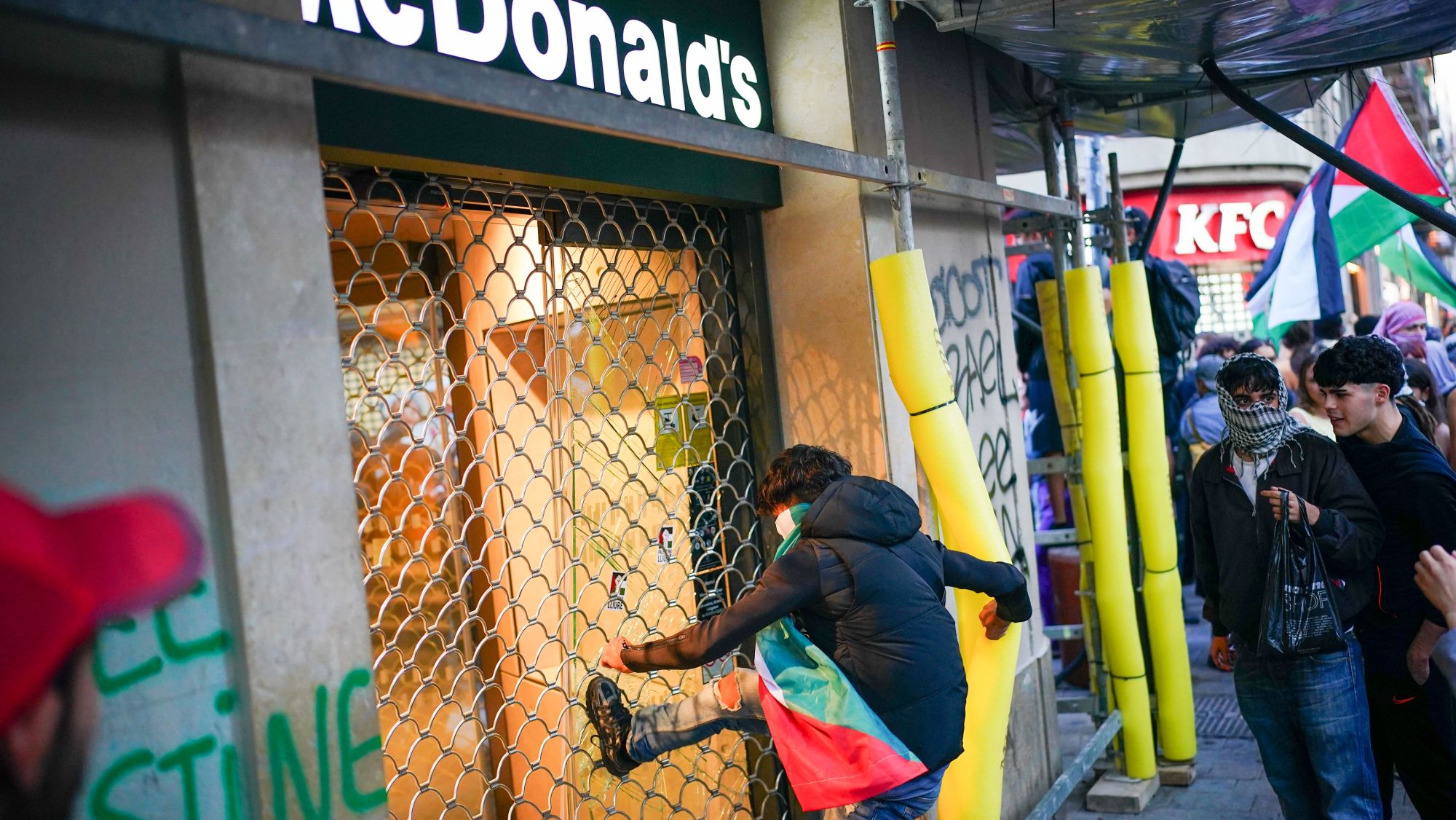 Un manifestant dona puntades a la reixa d'una coneguda hamburgueseria de la Rambla.