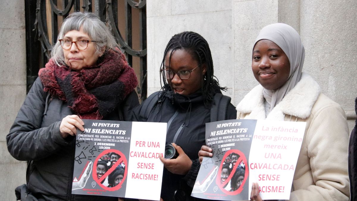 Tres manifestants amb els cartells exigint que no es pintin blancs de negre a la cavalcada de Girona