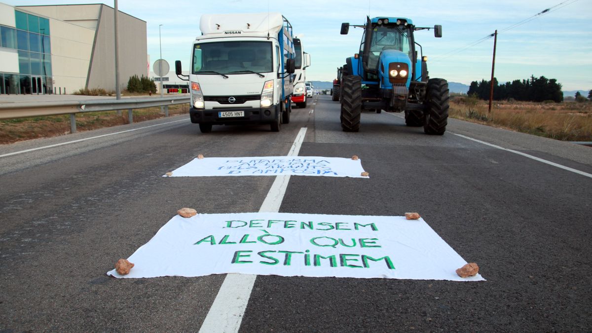 Cartell reivindicatiu, tractors i camions aturats al mig de l'N 340 a l'altura d'Amposta durant el tall fet per denunciar l'abandonament de les Terres de l'Ebre i reclamar mesures per millorar la gestió dels barrancs i inc
