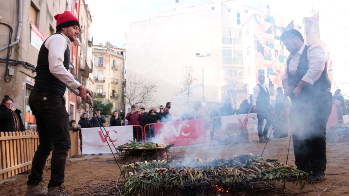Dos homes retiren de les brases calçots per ser cuits a la Gran Festa de la Calçotada de Valls