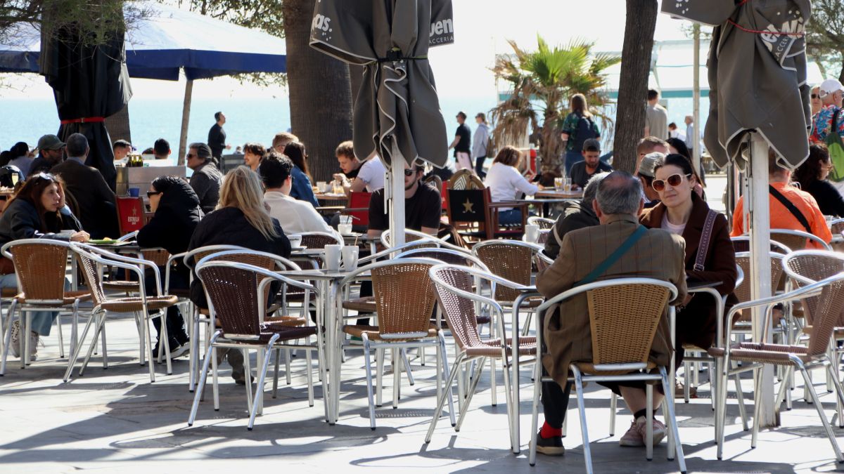 Gent gaudeix del sol i les vacances en una terrassa a la Barceloneta