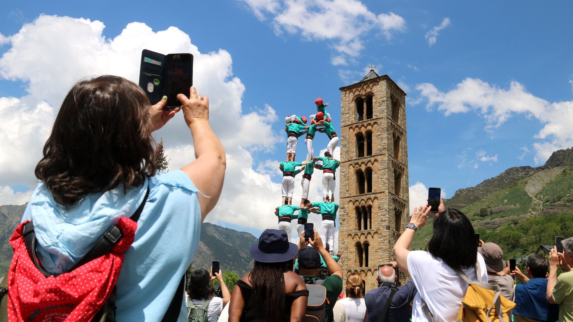 Una dona fa una fotografia als castellers de Vilafranca mentre fan un castell davant de l'església de Sant Climent de Taüll