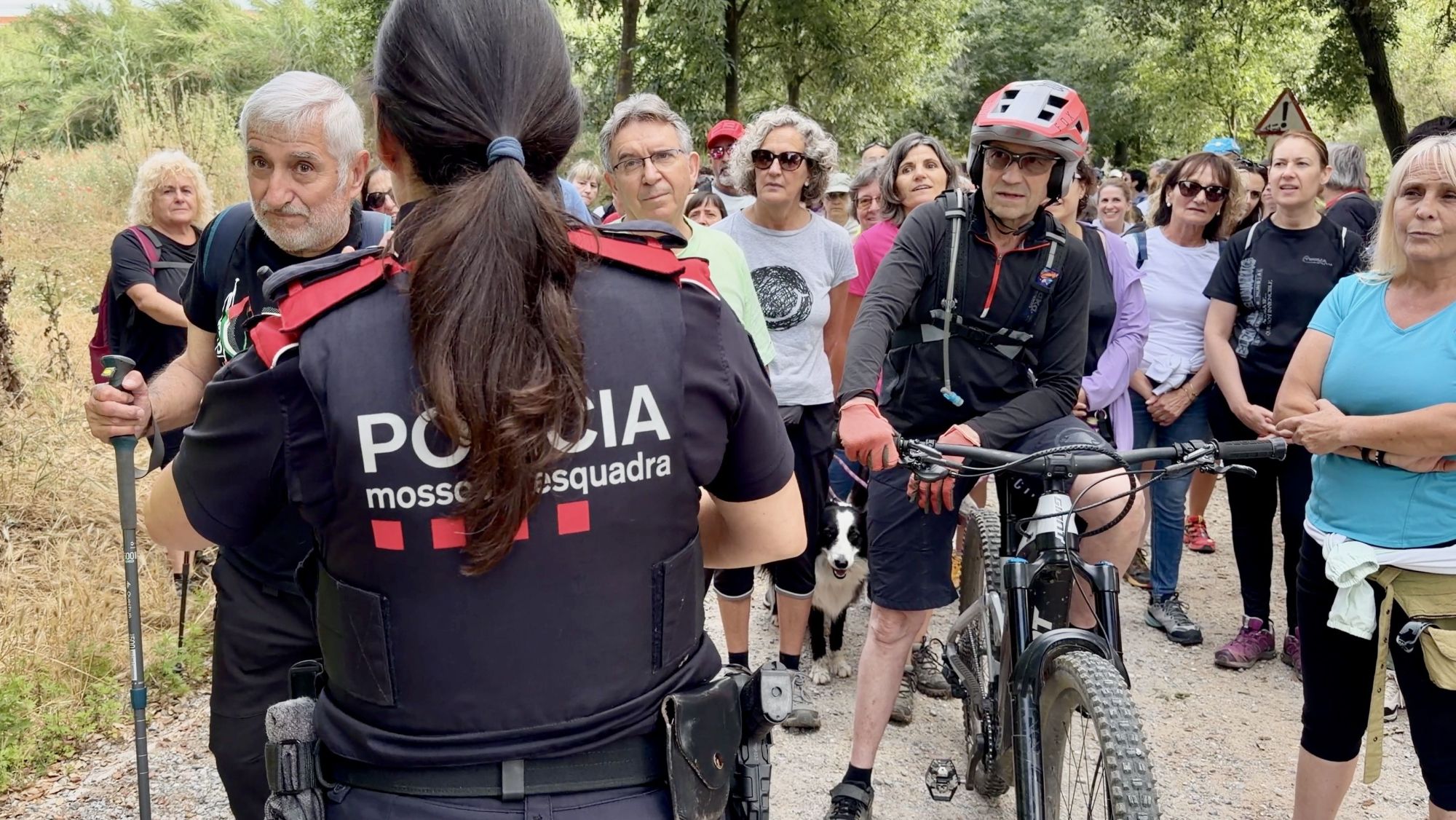 Una agent dels Mossos intenta indentificar els participants de la caminada reivindicativa per reclamar la reobertura de Collserola.