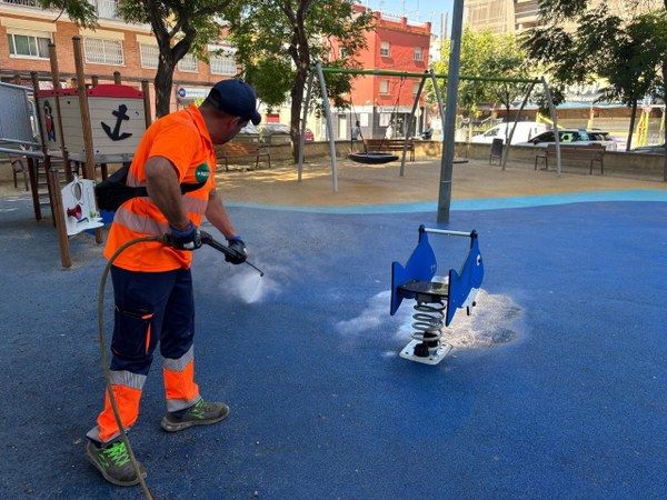 Un operari neteja un parc infantil de Cornellà