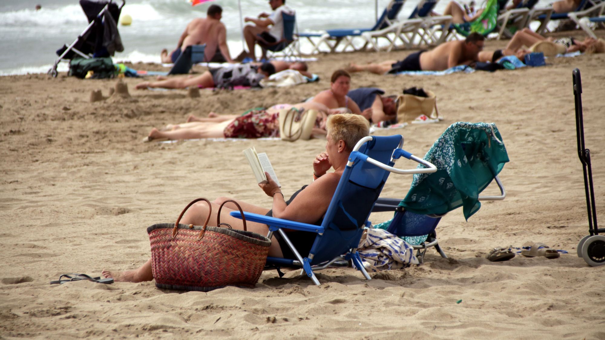 Una dona llegint un llibre a la platja de Roses