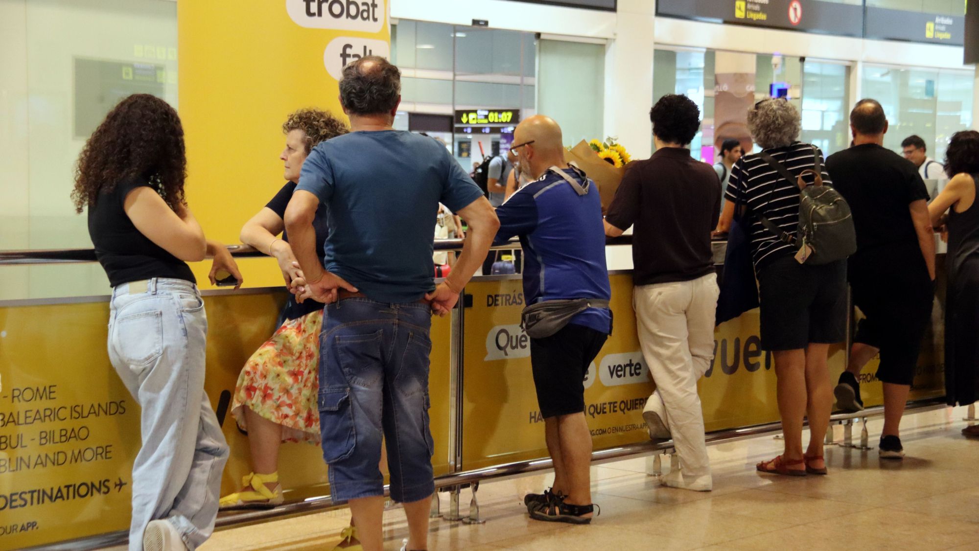 Usuaris esperen a la zona d'arribades de l'aeroport del Prat.