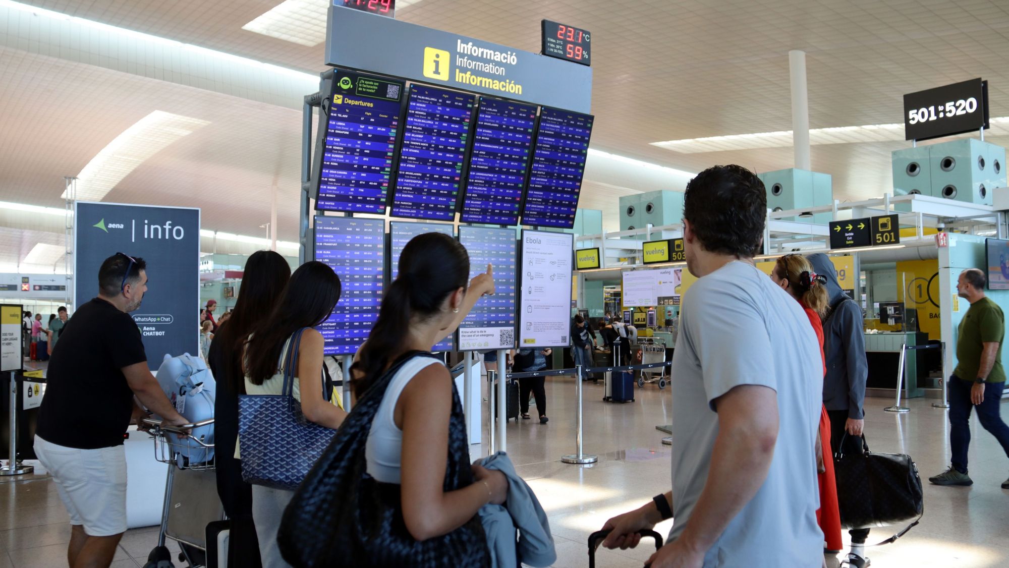 Viatgers mirant el taulell d'informació dels vols de l'aeroport del Prat.