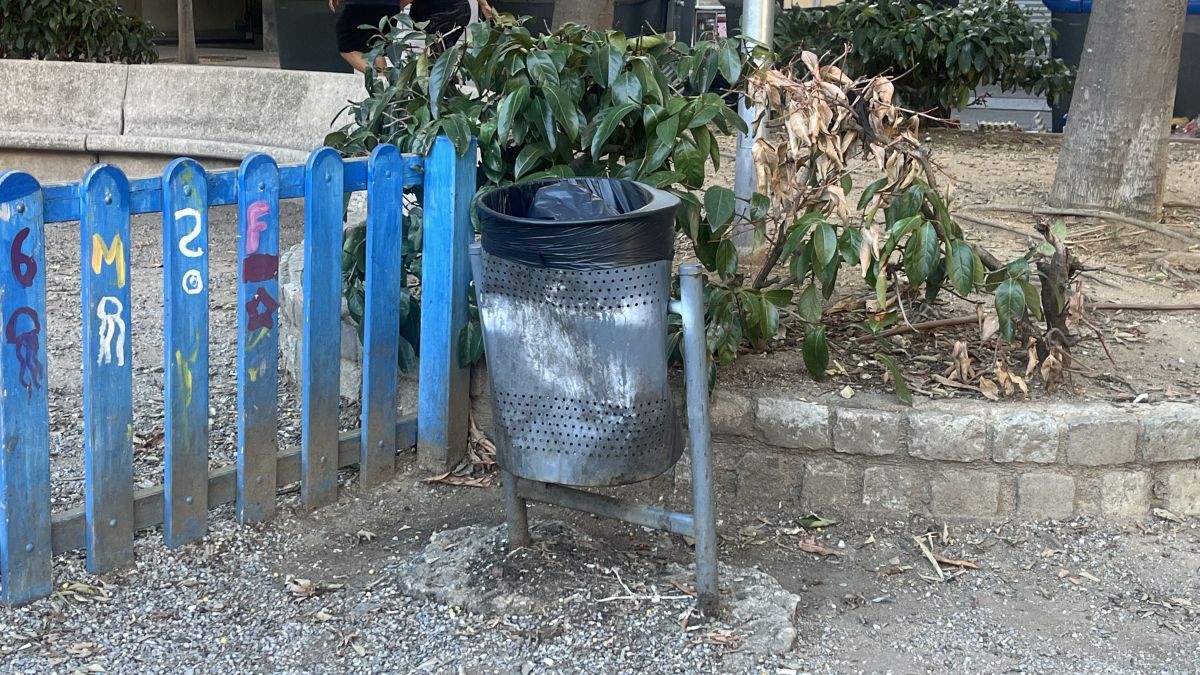 Una paperera destrossada i una tanca amb pintades a la plaça del Barco de Girona