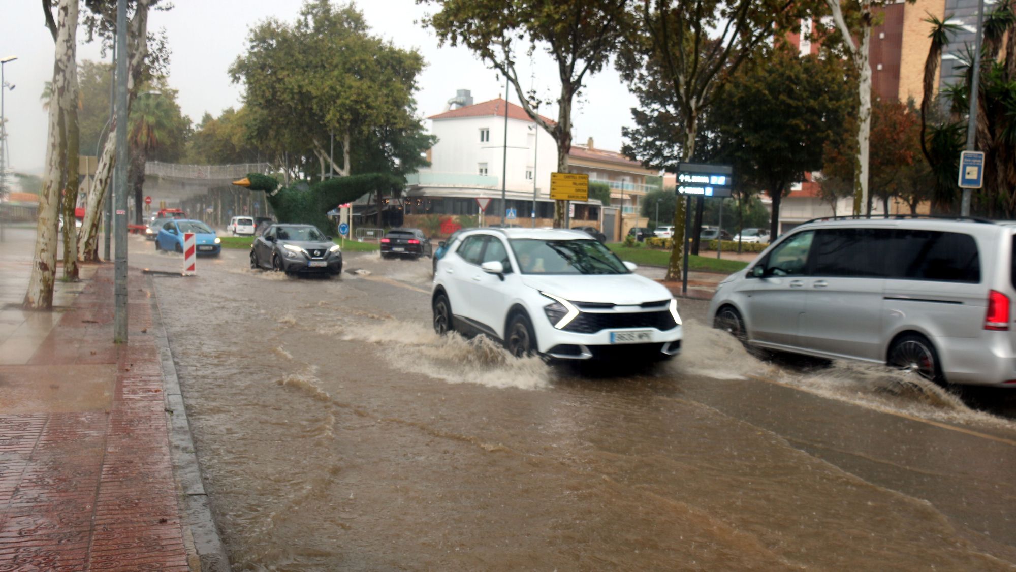 Cotxes aixecant aigua mentre circulen per l'avinguda S'Agaró durant el ruixat d'aquest dilluns a Platja d'Aro